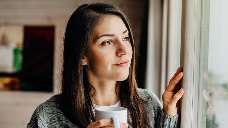 woman holding mug at window