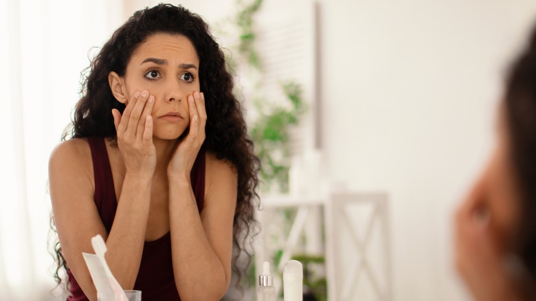 Worried woman checking her eyes in the mirror