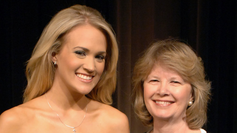 Carrie Underwood posing with her mother in front of a dark background