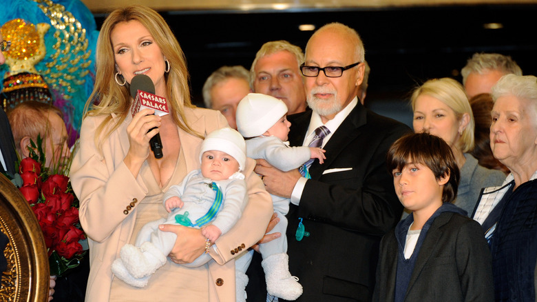 Céline Dion talking into a microphone with her family beside her
