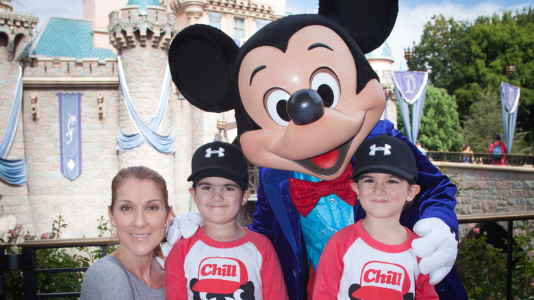 Celine Dion smiling with her twin sons and Mickey Mouse at Disneyland