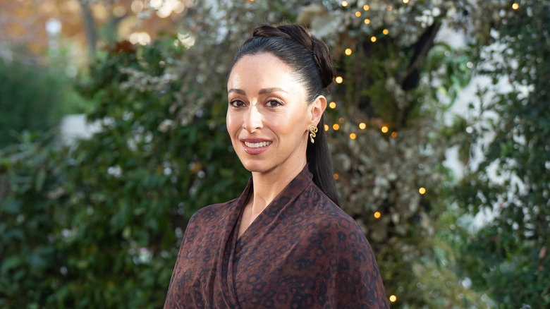 Oona Chaplin posing in front of greenery