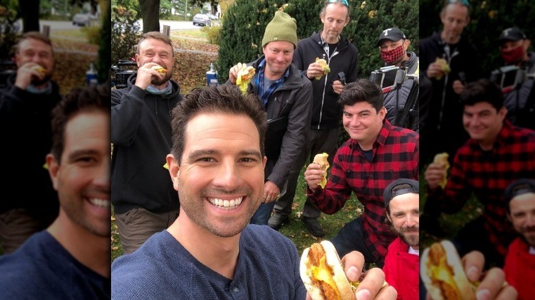 Scott McGillivray posing with the TV show crew and sandwiches