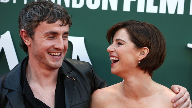 Jessie Buckley and Paul Mescal laughing on step-and-repeat