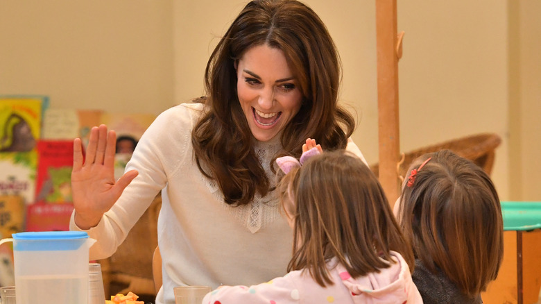 A laughing Princess Catherine high-fiving two little kids