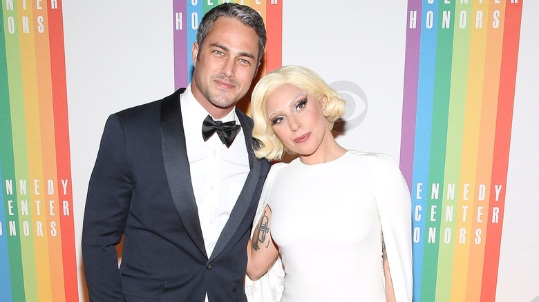 Taylor Kinney and Lady Gaga in front of signs for the Kennedy Center Honors