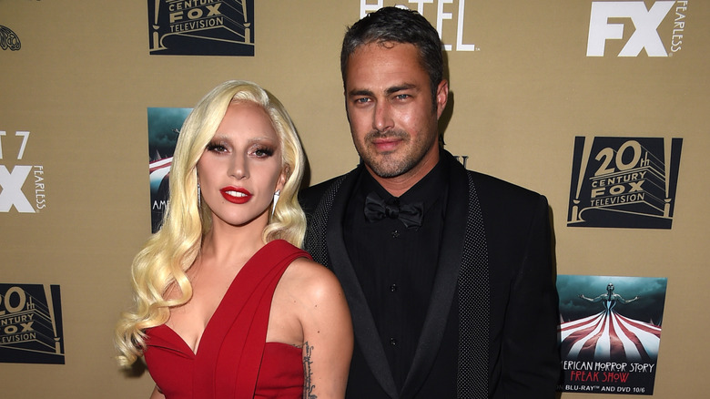 Lady Gaga wearing red and Taylor Kinney wearing black
