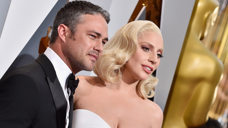 Taylor Kinney and Lady Gaga near a statue of an Oscar