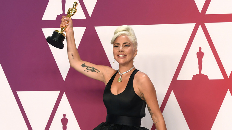 Lady Gaga raising her Oscar from A Star Is Born