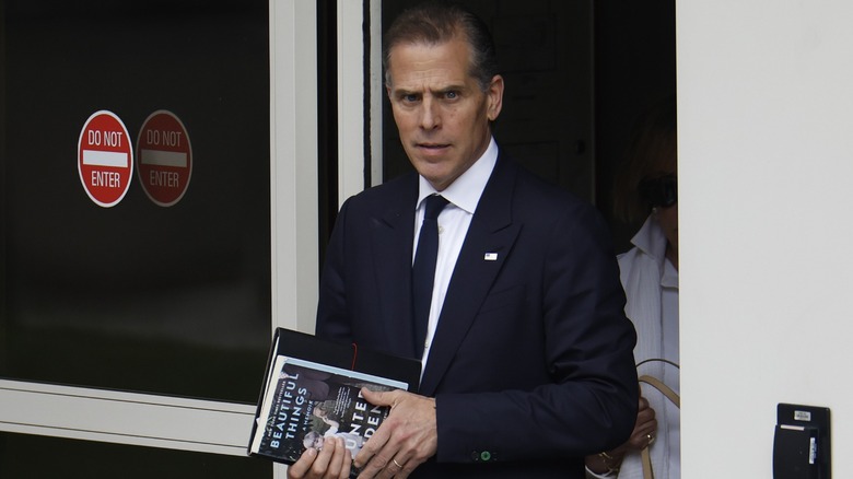 Hunter Biden exiting a building holding a copy of his memoir