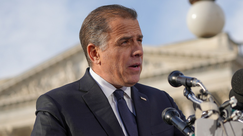Closeup, upshot of Hunter Biden delivering speech into several microphones outside