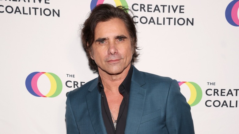 John Stamos posing in a teal blazer in 2026