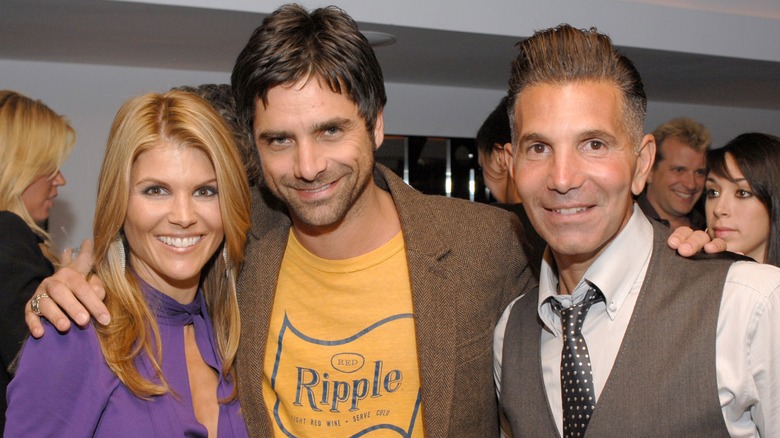 John Stamos standing between Lori Loughlin and Mossimo Giannulli
