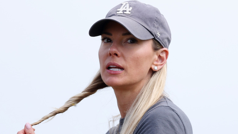 Erica Stoll wearing a baseball cap and touching her hair