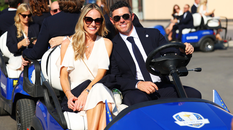 Erica Stoll and Rory McIlroy in a blue golf cart