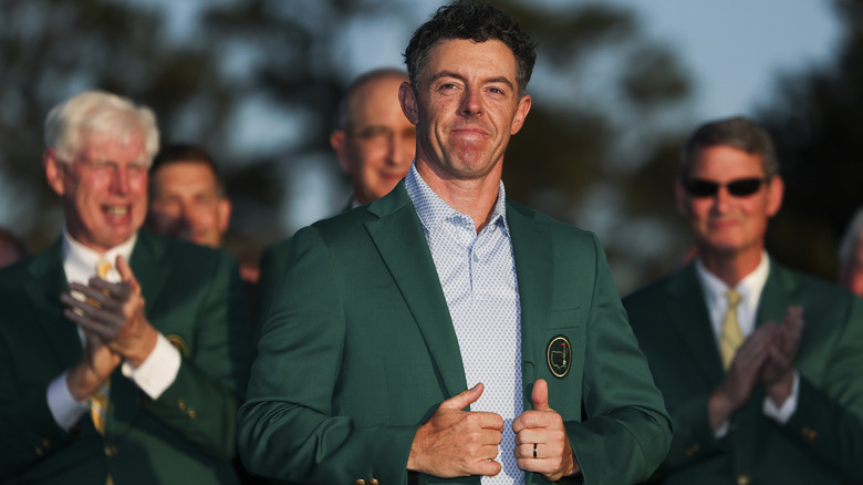 Rory McIlroy wearing a green suit jacket while giving two thumbs up