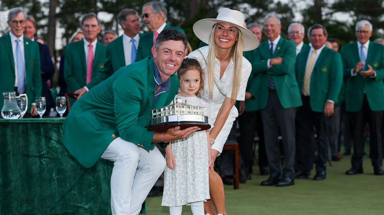 Rory McIlroy, Poppy McIlrory, and Erica Stoll with a trophy