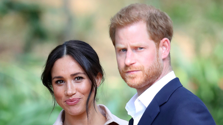 Meghan Markle pursing her lips and Prince Harry looking serious