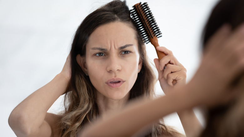 woman brushing hair looking into mirror