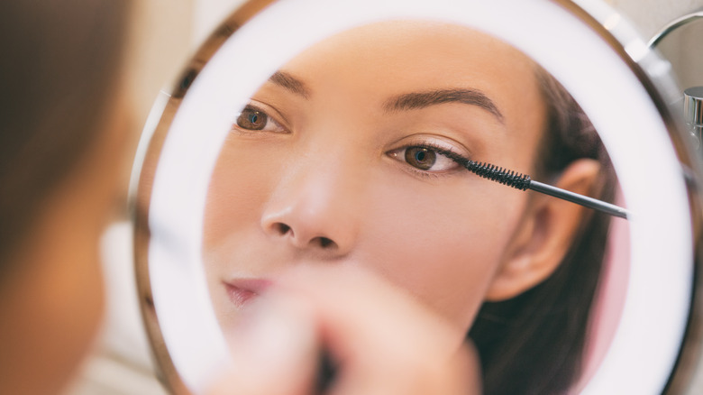 Woman applying mascara in mirror