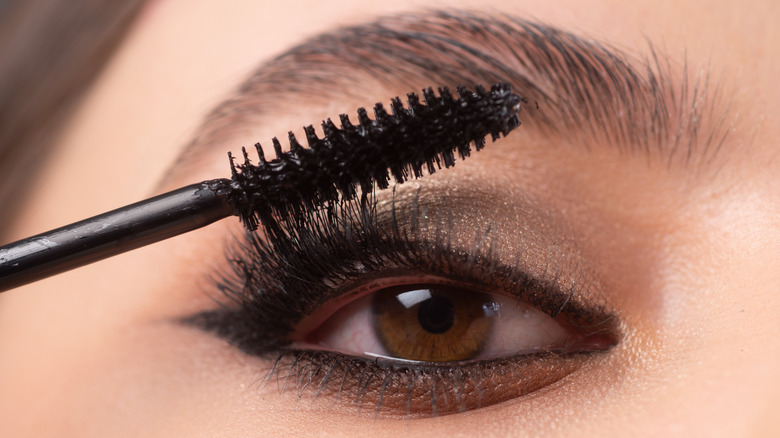 Woman applying mascara in lighted mirror