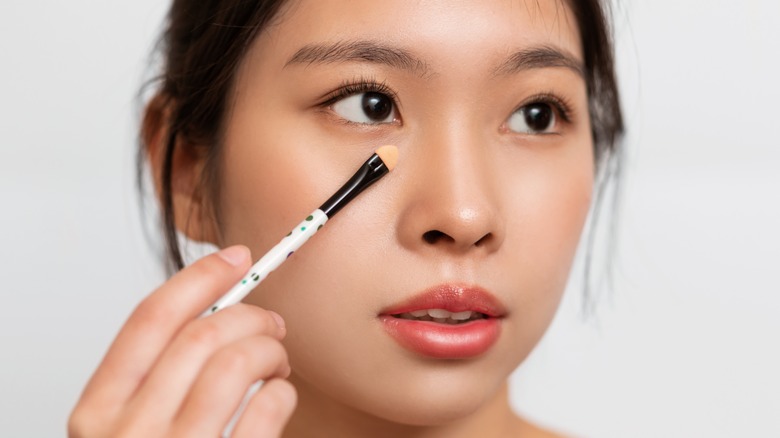 Woman applying concealer