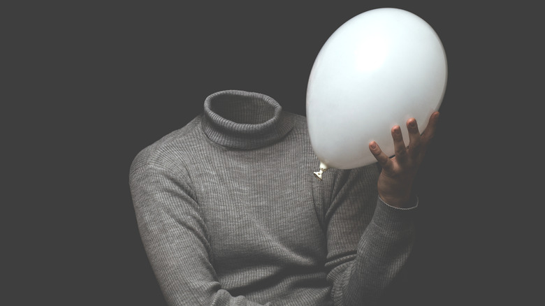 Headless man holding white balloon