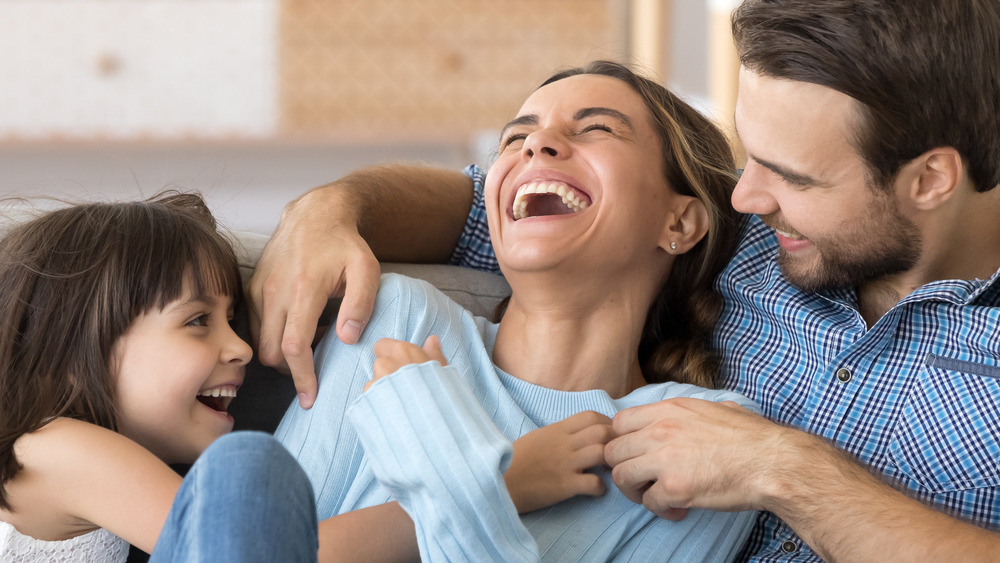 A man, woman, and little girl laughing