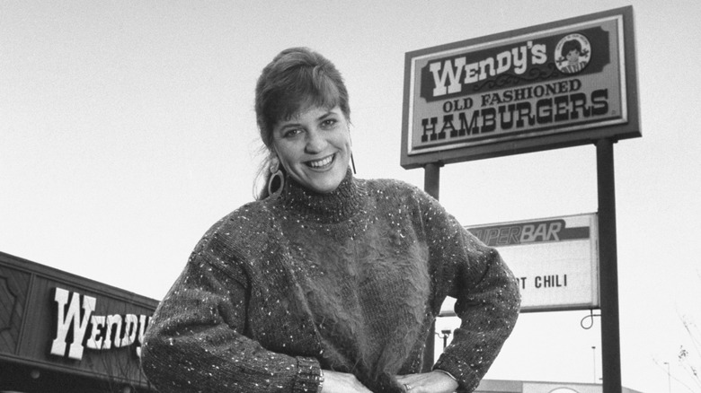 Wendy Thomas posing in front of a Wendy's sign and restaurant