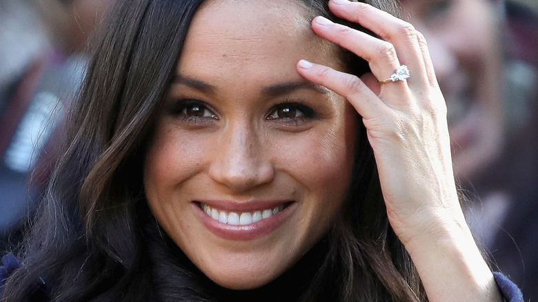 Meghan Markle smiling with hand on forehead