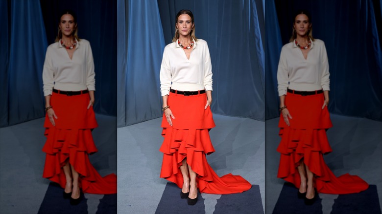 Kristen Wiig in a white and red dress on a blue carpet.
