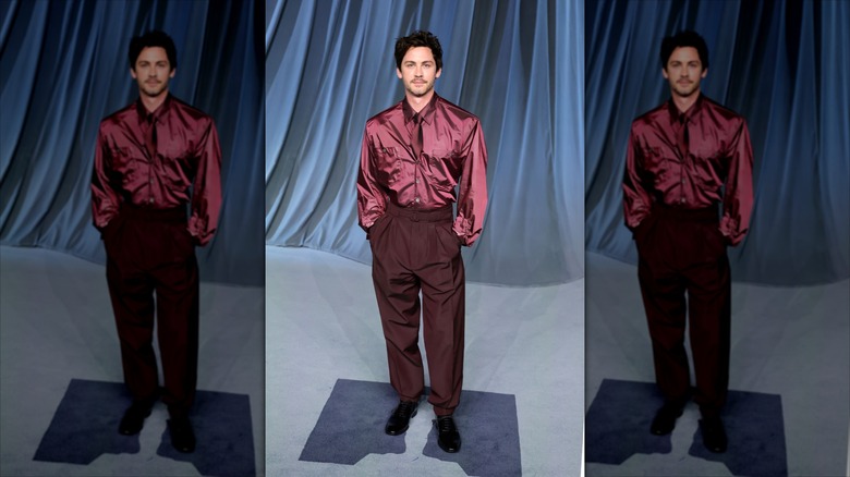 Logan Lerman in an all purple outfit with his hands in his pockets.