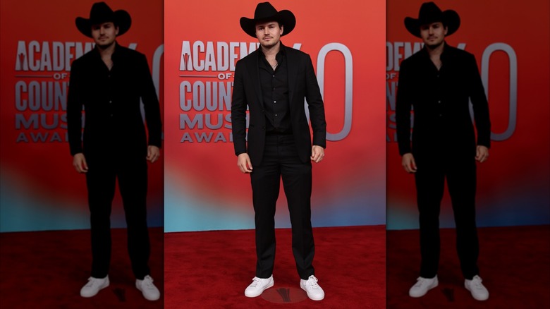 Kole Enright posing in an all-black suit and white shoes