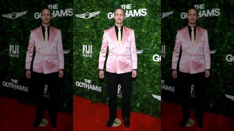Alexander Skarsgård posing in a pink jacket