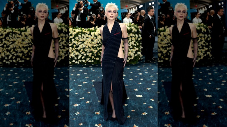 Emma Chamberlain poes in a black suit dress with cutouts