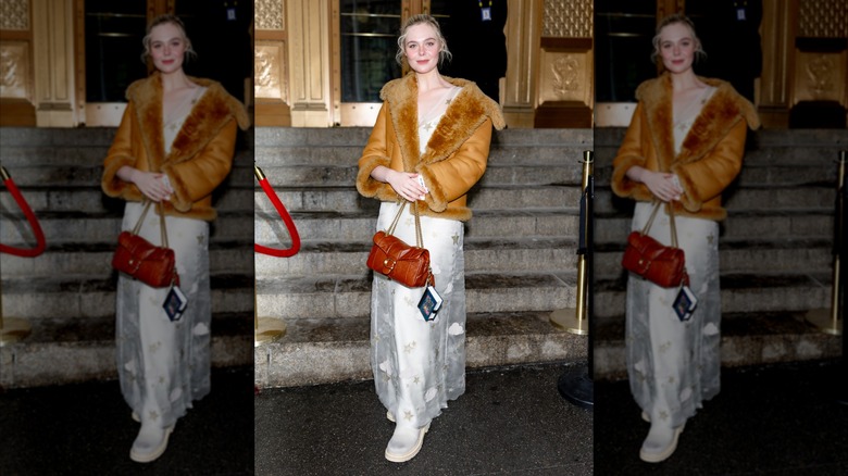 Elle Fanning crossing her arms and holding a purse