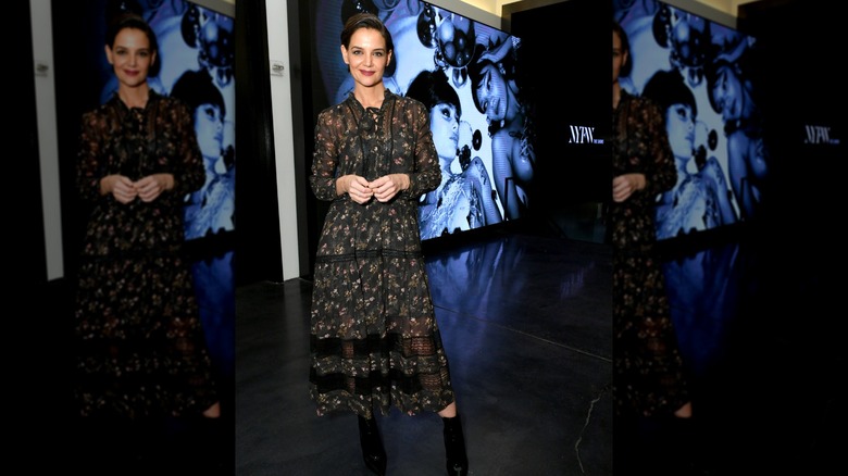 Katie Holmes standing with one leg to the side