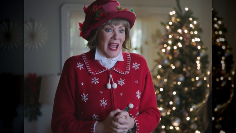 Jean Smart talking in front of a Christmas tree in a holiday-themed outfit