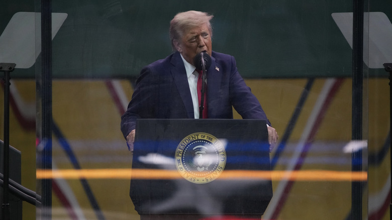 Donald Trump wearing a blue suit and red tie on stage at 2025 military parade