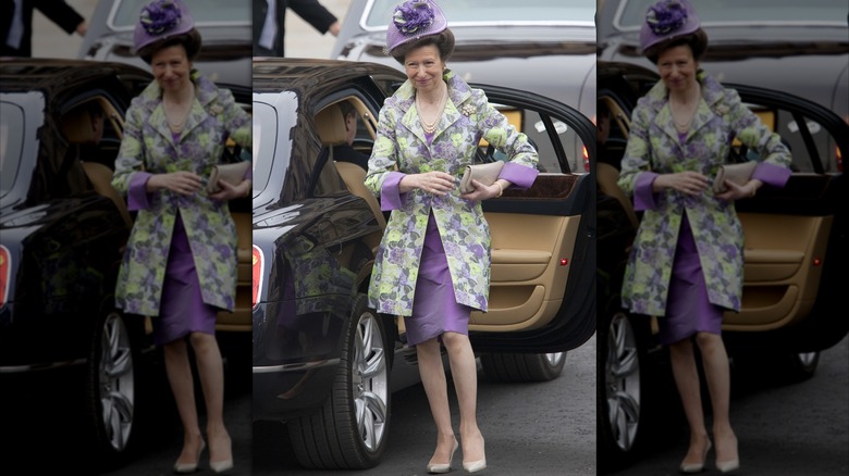 Princess Anne in purple floral outfit standing next to car