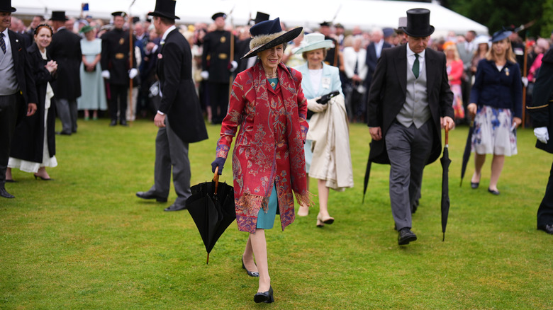 Princess Anne walking in a crowd with an umbrella