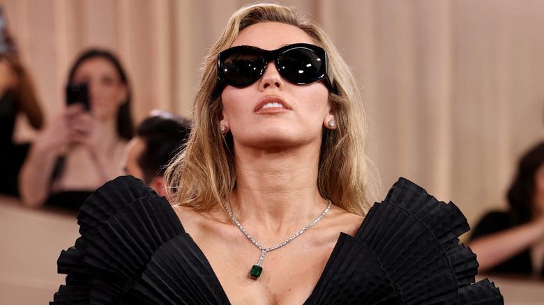 Miley Cyrus looking up while wearing sunglasses