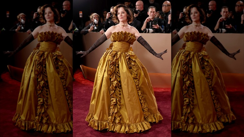 Parker Posey wearing a yellow ballgown with ruffles