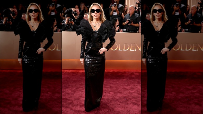 Miley Cyrus wearing a black sequined dress with large ruffles on the shoulders and black sunglasses