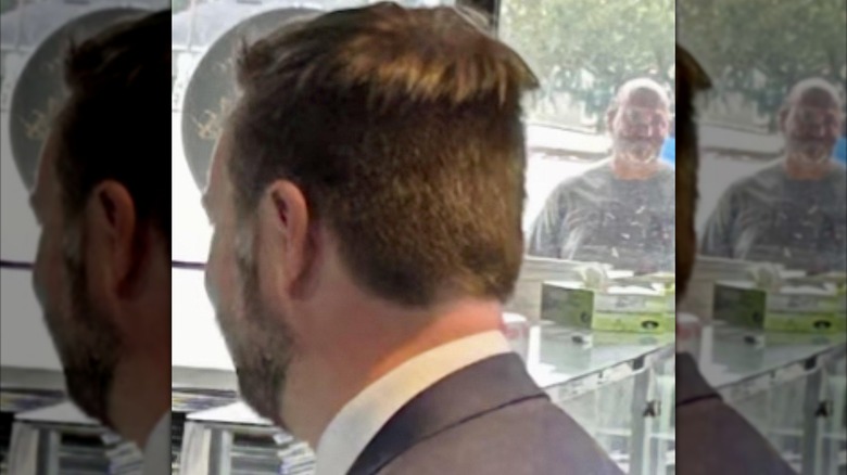 Vice President JD Vance stands with his back to the camera, sporting a half-undercut hairstyle