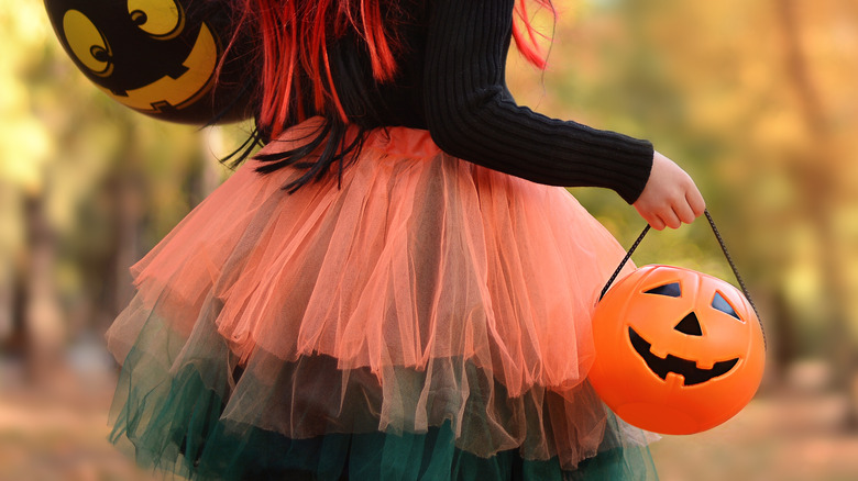 Woman in a Halloween costume holding pumpkin basket