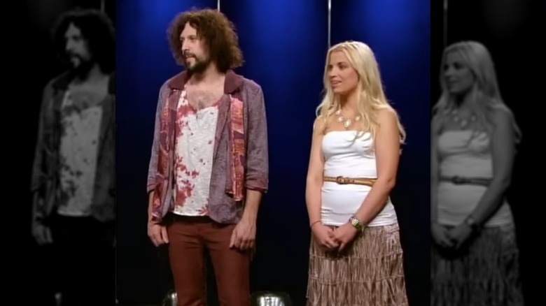 A model wears a burgundy and purple outfit on "Project Runway," with designer Laura Kathleen by his side