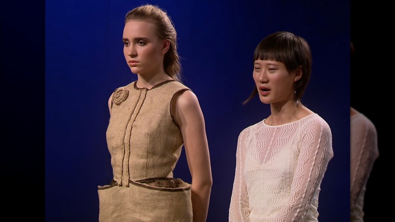 Ping Wu and model talking to judges about the burlap sack design on "Project Runway"