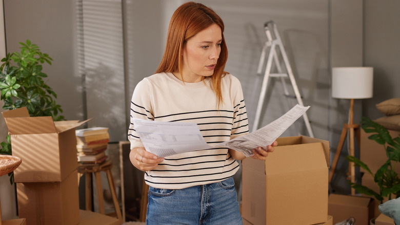 Woman looking at papers while surrounded by boxes