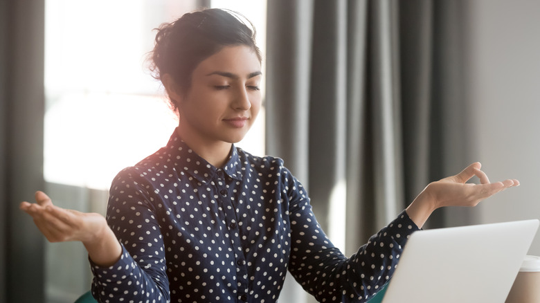 Woman in meditative pose at laptop